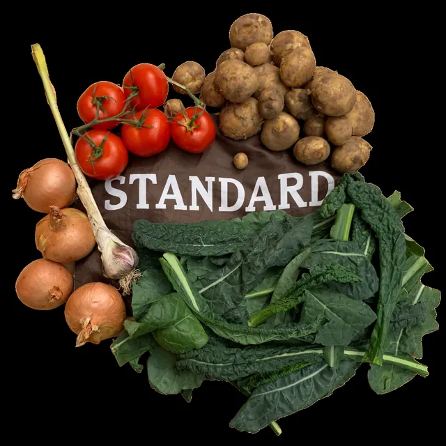 The contents of a Standard bag laid out: cavolo nero, potatoes, tomatoes, onions and garlic