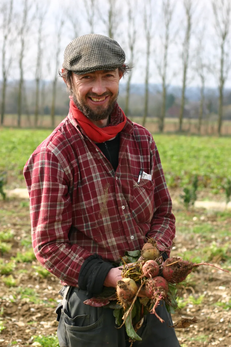 Martin of Ripple Farm smiling in a field, holding a bunch of freshly pulled beetroot