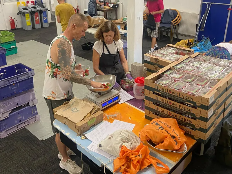 Two volunteers weighing strawberries at the packing table